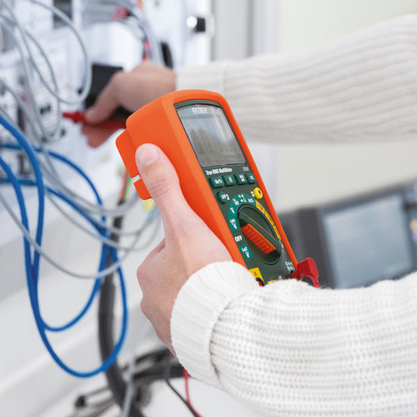 Student taking electrical measurement with multimeter on the EV charging station
