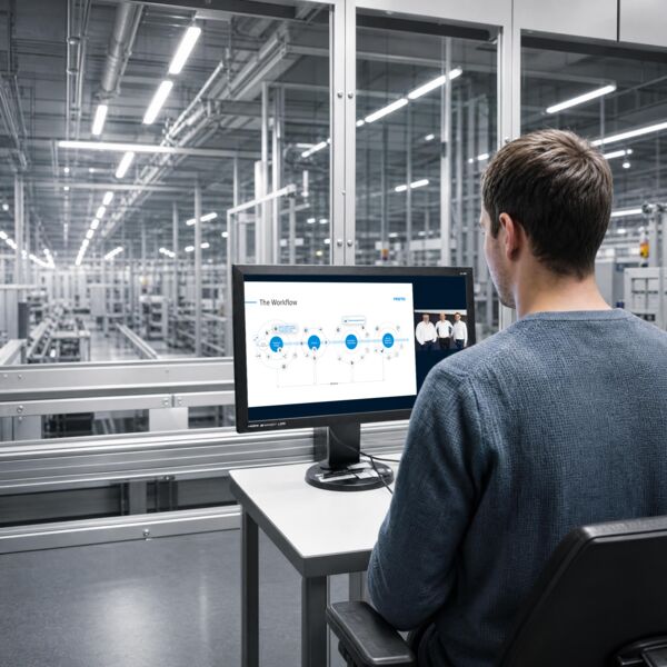 A person sitting in front of a laptop watching a webinar, with an industrial background.